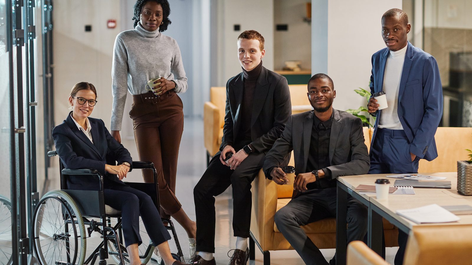 Une équipe diverse, dont une jeune femme en fauteuil roulant, réunie dans un bureau lumineux.